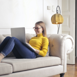 woman sitting on couch using laptop inside condo