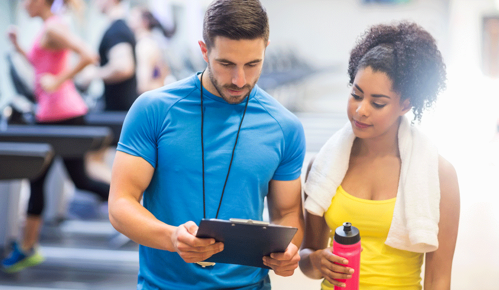 fitness trainer and woman looking at clipboard